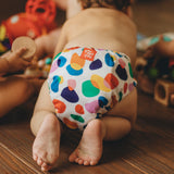 Diseño divertido y práctico de Poo and Pebble - panal ecológico reutilizable llevado por un bebé jugando juguetes con amigos