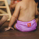 Niños sentados en el suelo con el pañal lavable y atractivo Purple Poo