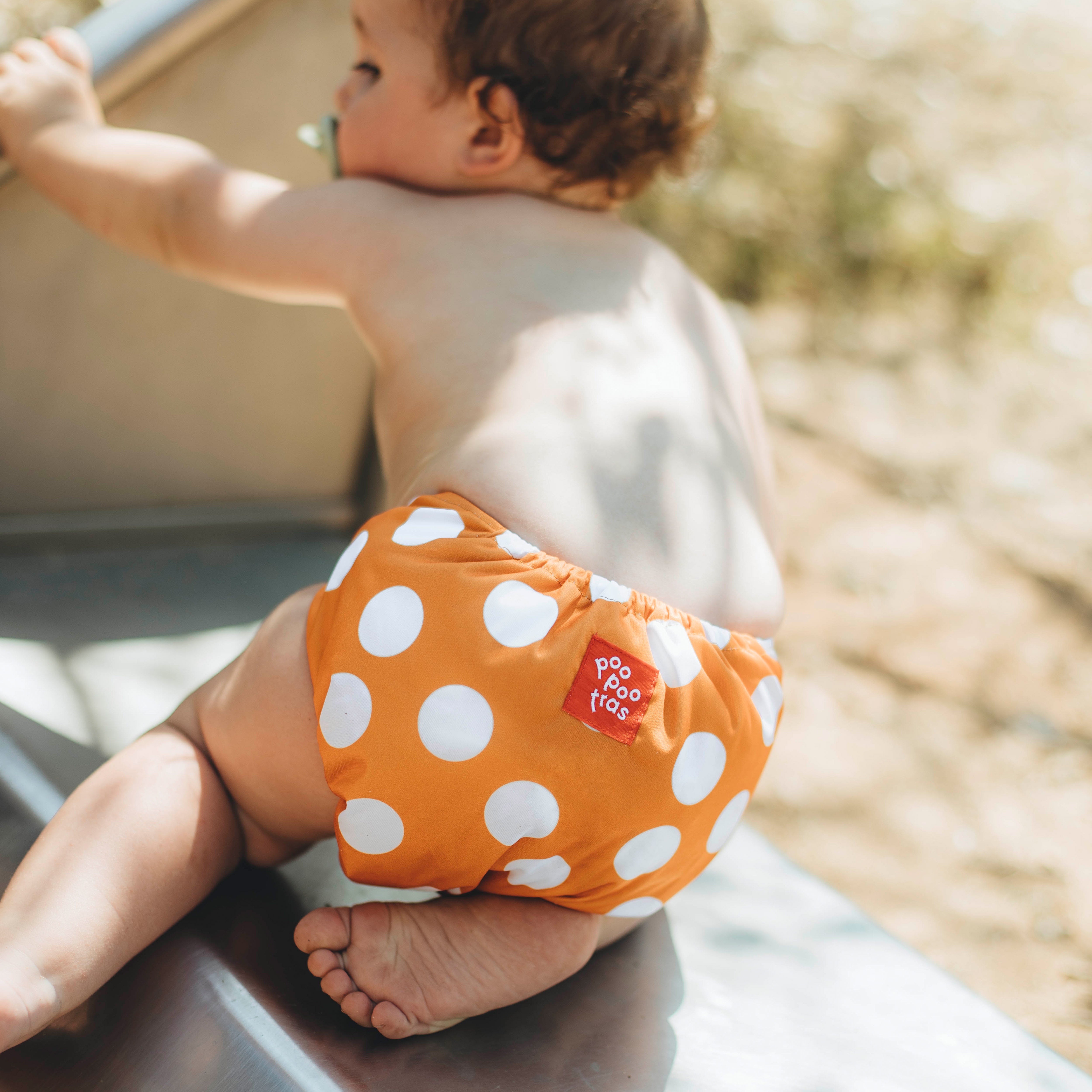 Pañales de tela reutilizable Ole ese poo llevado por un bebé jugando solo en el patio